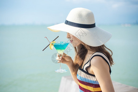 美丽的女人正在海滩喝冰水夏天在海滩喝水夏天的概念图片