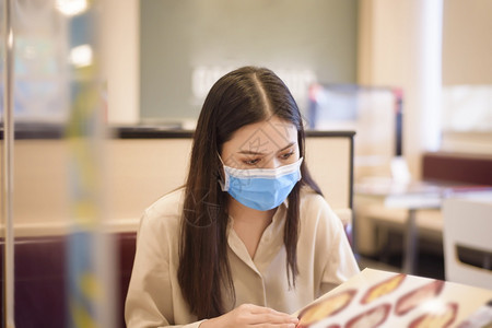 由于科罗纳大流行女在餐厅吃着社会迷魂药而新冠大流行图片