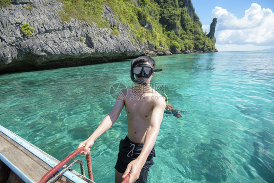 泰河传统长尾船的活跃男子准备在泰国菲群岛俯冲和潜水图片