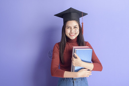国外学生素材具有紫背景毕业上限的年轻大学女生的肖像背景