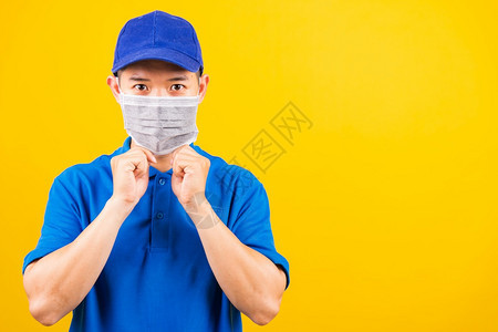 身穿蓝色T恤衫和制服的亚洲年轻送货工人身穿蓝色T恤衫和帽子制服的亚洲年轻送货员身着面罩在检疫大流行冠状COVID19下保护服务客背景图片