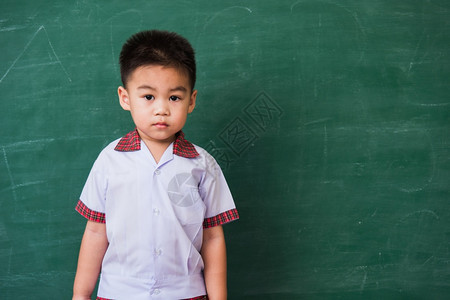 快乐的亚洲可爱小孩男从幼儿园的稚穿着学生制服的微笑在绿色学校黑板上第一次到学校教育概念摄影棚拍图片