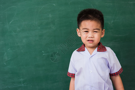 快乐的亚洲可爱小孩男从幼儿园的稚穿着学生制服的微笑在绿色学校黑板上第一次到学校教育概念摄影棚拍图片