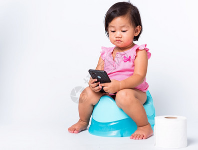 亚洲可爱的小婴儿女教育培训他们坐在蓝室锅或便壶上用卫生纸卷玩智能手机在白色背景上单独拍摄工作室Wc厕所图片