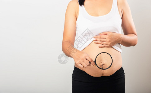 亚洲母女特写镜头用放大镜显示妊娠纹松弛的小腹皮肤她怀孕后肥胖婴儿出生隔离在白色背景上健康的腹部多余的身体概念背景图片