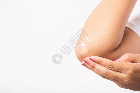 闭亚洲年轻女在手肘上施润肤霜背景图片