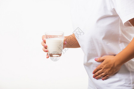 近身不宽容的年轻女子使用手握着玻璃牛奶她胃痛得要命有坏的乳糖不耐与奶食品不健康的问题图片