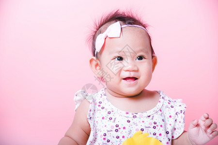 亚洲女孩的肖像小可爱的婴儿微笑着快乐的面孔粉红背景图片