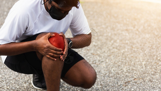 在户外街头健康公园跑动时黑人男子戴着手表握着膝盖疼痛身体运动因锻炼概念而受伤图片