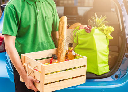 提供新鲜蔬菜食品和水果后车用木篮子装满送女顾客回家门口背景图片