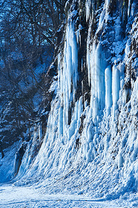 大冰柱挂在河岸悬崖上蓝色背景图片