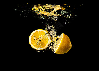 新鲜黄色柠檬在黑背景的喷水中流出有很多气泡刷新概念图片