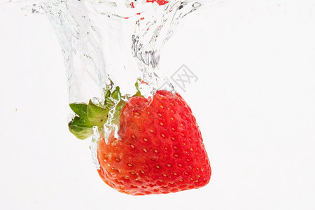 新鲜草莓落入清水中白底分离喷洒白底水中分离喷洒抗氧化剂概念新鲜草莓投入清水中图片