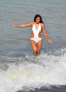 美丽的年轻女子在海洋玩耍穿着白泳衣的海浪玩得开心图片