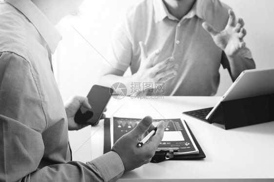 商界人士合作编制文件在现代办公室使用智能电话数字平板脑和笔记本黑人和白图片