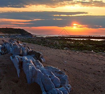 从海滩向日落的岸看大石块靠近法国圣让德卢斯比凯湾图片