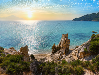 希腊恰尔西迪斯图尼亚半岛普拉塔尼西海滩附近的日落沙滩和岩石海岸图片