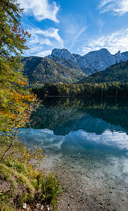 秋天的山阳光明媚多彩的秋天风景和平的山湖水反射清晰上奥地利兰巴西恩湖背景