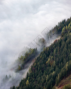 横跨阿尔卑斯山丘的有线汽车通龙多拉斯从迷雾云向顶端移动秋雾晨景图片流季节云和迷雾天气状况背景场图片