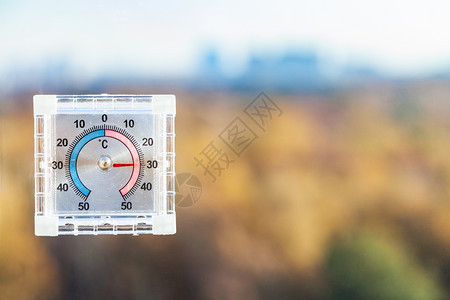 家庭窗户的外温度计和炎热秋天的模糊城市公园图片