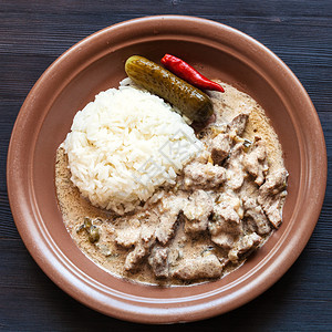 俄罗斯料理棕色盘子配一部分牛肉酸奶油炖肉和煮米饭图片