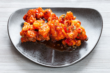 朝鲜菜料在Kkkanpunggi辣大蒜炸鸡肉和甜辣酱蔬菜黑盘上贴图片