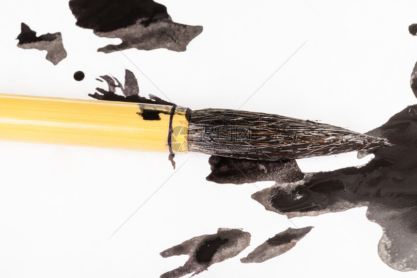 黑漆的圆山羊毛竹刷子在白纸上的墨迹涂漆图片