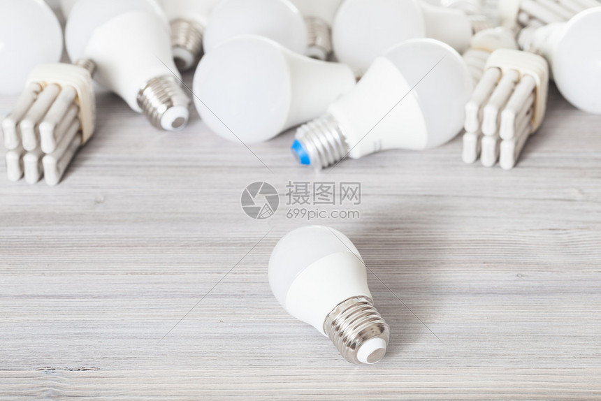 一个白色LED灯泡光和灰色木板上各种节能灯图片