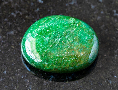 印度黑色花岗岩背景的绿色阿文图林宝石图片