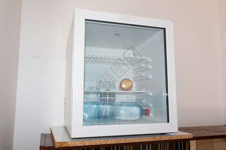 酒店电气苏打罐和水瓶放在一个小冰箱里在旅馆有玻璃门瓶子背景图片
