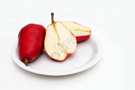 切片碟子水果梨白上切成红梨的子被切成两半显示核心和种子图片