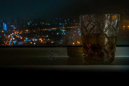 合适的散景为了威士忌玻璃放在该市旅馆房间窗户旁边有外部观车前灯光照亮了汽车头灯适于制作背景图象供广告使用b于宣传背景图片