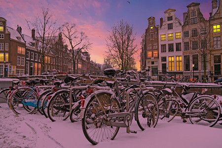 家日落时荷兰阿姆斯特丹的雪地自行车运输城市图片