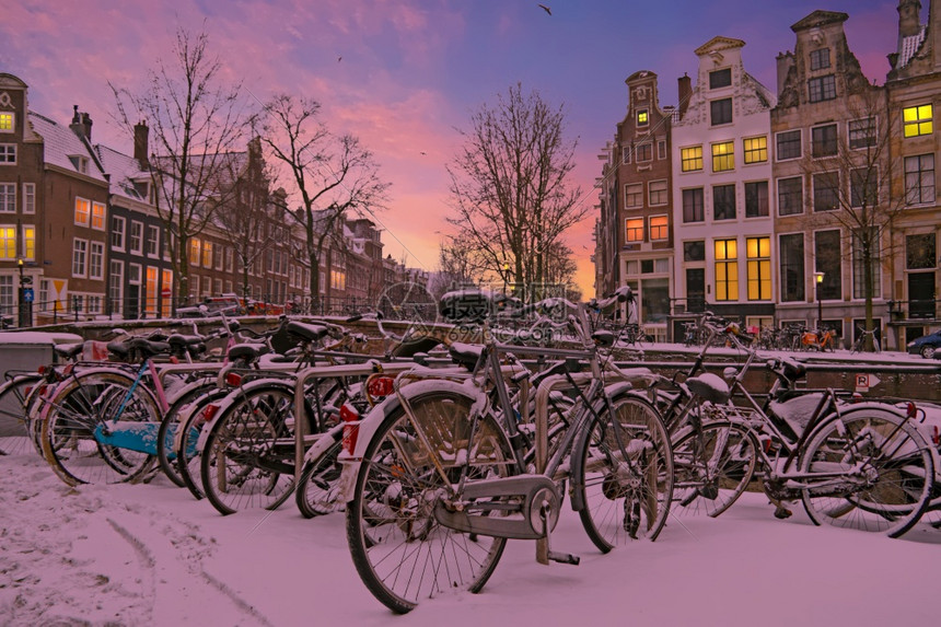 家日落时荷兰阿姆斯特丹的雪地自行车运输城市图片