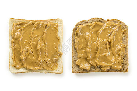 脆的两片白色和全麦面包被花生酱覆盖的照片白纸上隔着食物健康图片