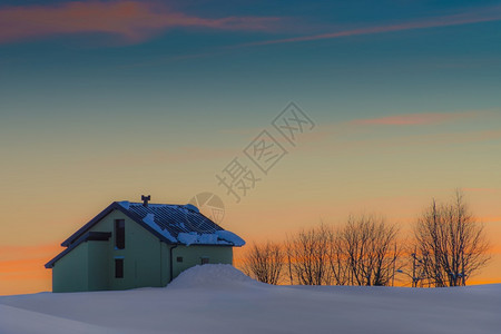 夕阳下的雪中小屋图片