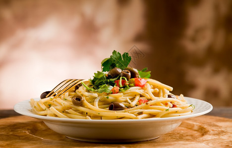 美味的素食意大利面盘配有橄榄和木制餐桌上的欧斯利地中海美食健康图片