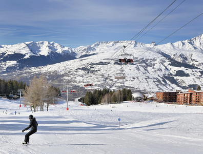 阿尔卑斯山度假胜地的雪坡和蓝色天空下的缆车图片