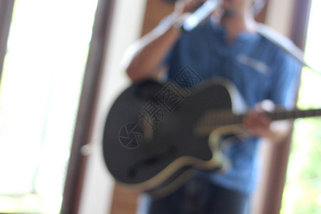 工作室男人音乐家弹吉他时用手握着麦克风拍音乐家弹吉他时的模糊照片玩图片