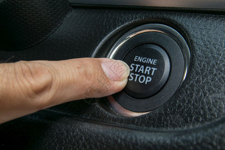 手指点火按启动引擎的汽车司机图片