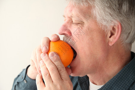 营养老男人咬橘子开始剥皮过程年长的食物高清图片