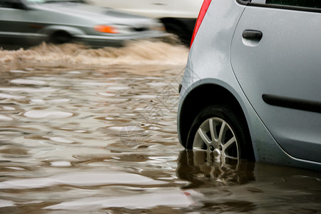 水淹车停車處安全危险的白天下雨后在水淹路上停车的灰色汽背景