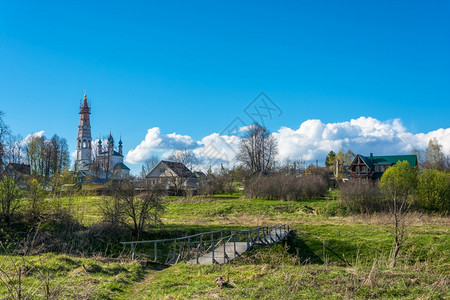 无蚊村美丽的绿色Mikhailovskoye村的景象与圣大教堂Michael教堂和在桑尼春日无生物宿主的景象晴天背景