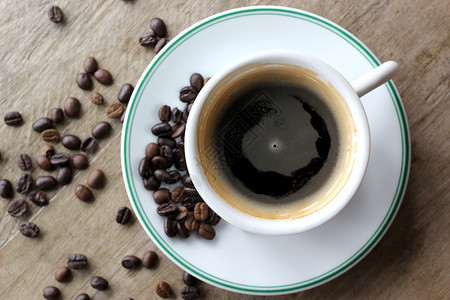 黑色的早晨咖啡杯木制桌上有豆子泡沫图片