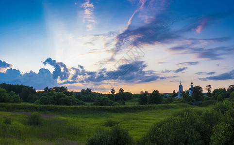 蓝色的美观明云全景在日落的光芒中和白教堂的钟塔俄罗斯美丽的晚上图片