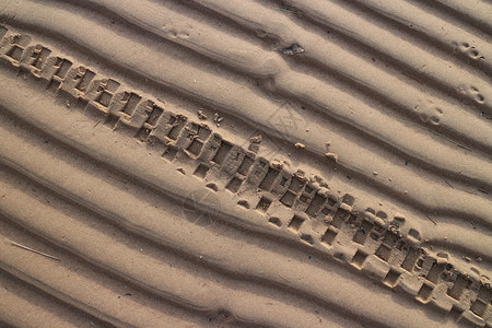 小路一种污垢摩托车轮在海滩沙上的印图片
