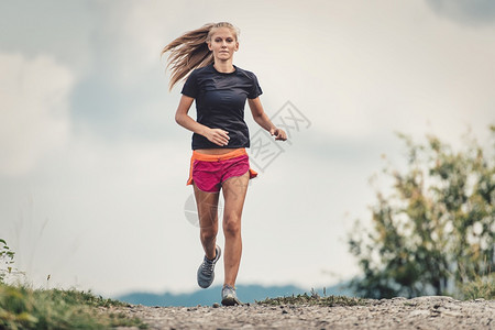 金发美女运动员在山丘的泥土路上跑运动的身体景观图片
