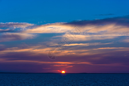 夏天丰富多彩的海滩白明亮美丽日落深蓝水和紫色云彩图片