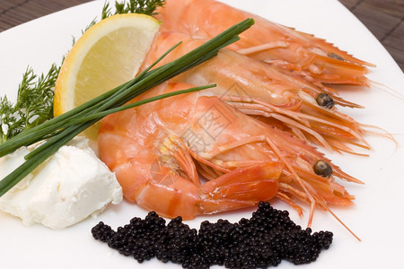 虾和鱼子酱一个配有新鲜鱼子酱小虾和的盘子黑色柠檬烹饪图片