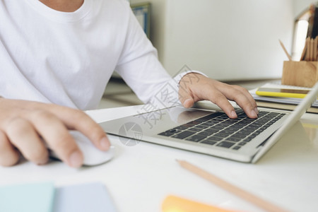 键盘手电子邮件在互联网上家书桌做笔记本电脑工作的青年男子贴近手轻电话背景